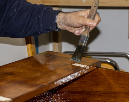 A close-up of the Maintenance member varnishing the chart table.