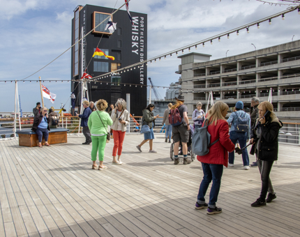 Visitors standing on the outside Verandah Deck at Britannia listening to the audio guided tour. 