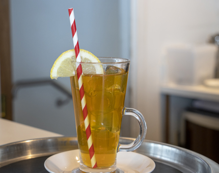 An iced tea served in a tall glass with a slice of lemon. 