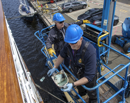A close-up of the two Maintenance men treating the hull. 