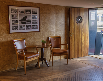 The Reception at Fingal with a small table, two chairs and black and white historical photographs of Fingal on the wall. 