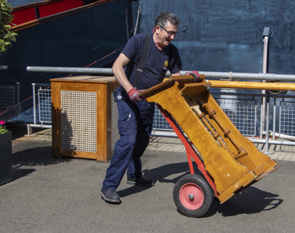 A Facilities Officer moving a podium on a trolley on the Quayside. 