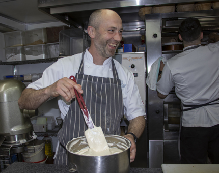 A Chef mixing a bowl of sponge with a spatula in the Galley.