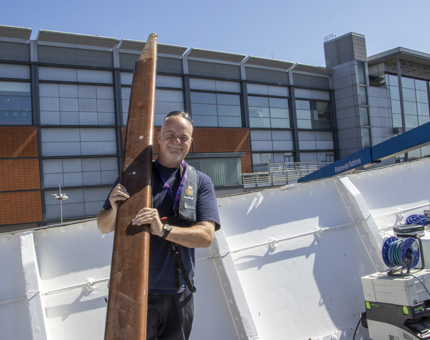 A man from the Maintenance team holding a wooden handrail on the Fo'c'sle deck. 