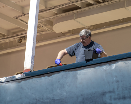 A view from the outside of the hull as the Maintenance team member is painting. 