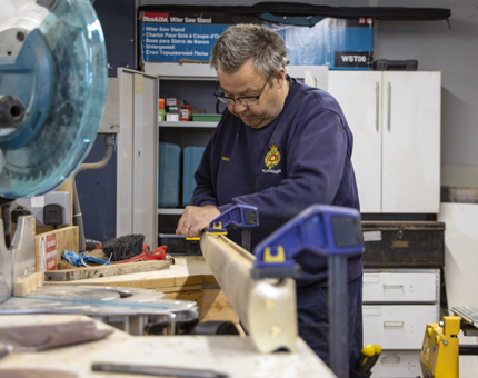 A member of the Maintenance team working on a handrail in the workshop.