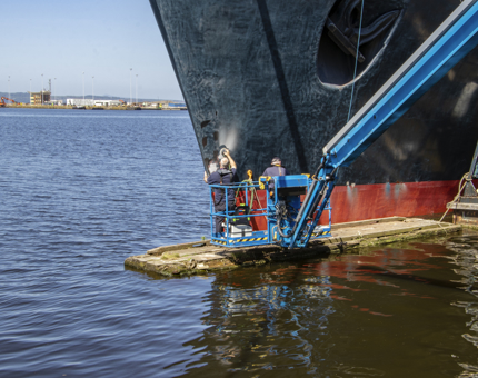 Two men working on the hull in the water. 