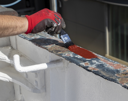 A close-up as primer paint is applied with a paintbrush. 