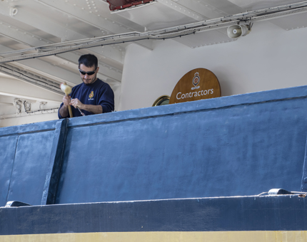 A man from the Maintenance department using a hammer to remove adhesive from underneath handrails. 
