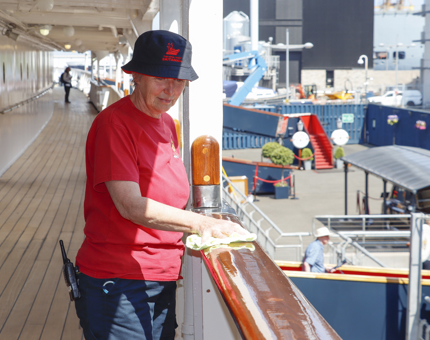 A Housekeeper is polishing a handrail in the sunshine. 