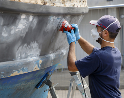 A man is sanding the paintwork on a boat.