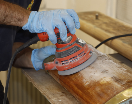 A more detailed view as a member of the team sands a wooden handrail. 