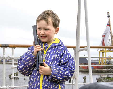 A little boy listening to the audio guided tour on the outside deck of Britannia. 