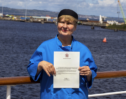 A woman holding a letter from Buckingham Palace. 