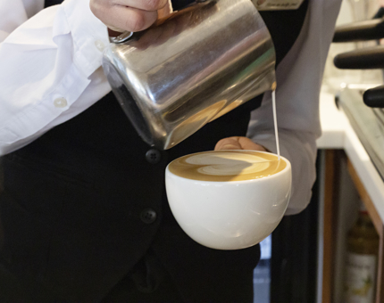 A close-up of a barista pouring a coffee. 