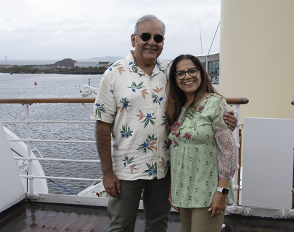 A smiling couple pose standing on the Bridge.