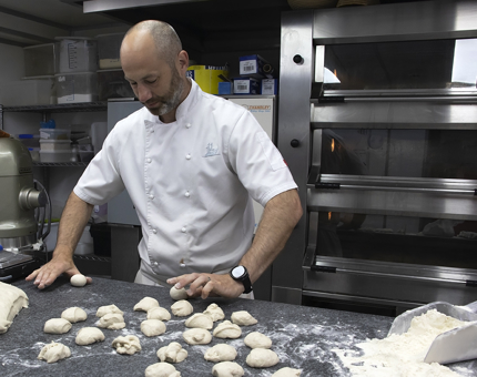 A Chef making bread rolls in the Galley. 