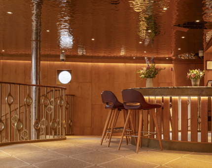 Two bar stools are at the bar in Fingal Hotel's Ballroom. The ceiling is reflecting the lights. 