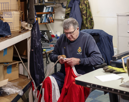 A man holding a string of red flags, mending them.