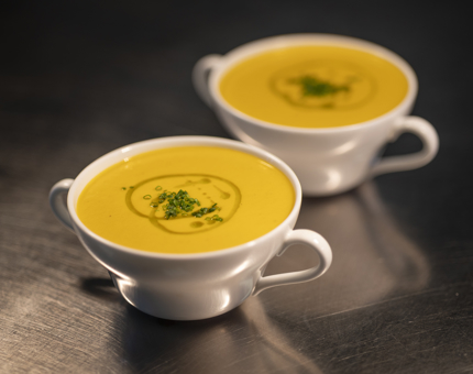 Two bowls of cream of carrot and sweet potato soup on the Galley bench. 