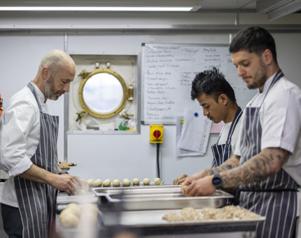 Three Chefs in the Galley making bread rolls. 