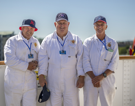 Three men wearing white overalls modelling Britannia branded hats, which are available in our Shop. 