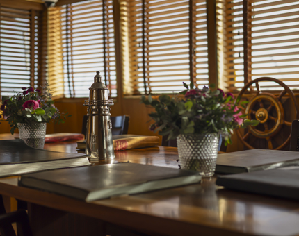 Fingal Hotel's Bridge. The table is set with log books, a silver lighthouse vessel and flowers. 