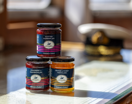 Three jars of jam and marmalade stacked. 