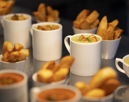 Mugs of soup and bowls of potato wedges waiting to be served.