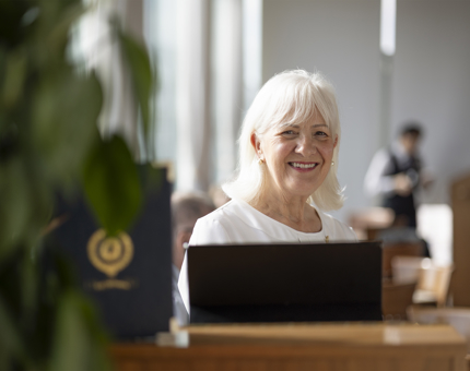 In the Royal Deck tearoom, the host is standing behind a podium smiling. 