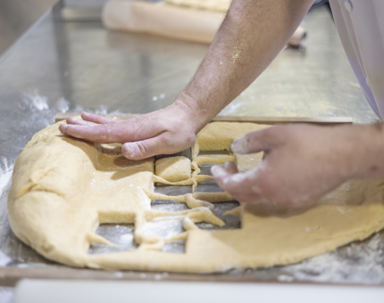 A close up of a Chef's hands cutting scones from dough in the Fingal Galley.