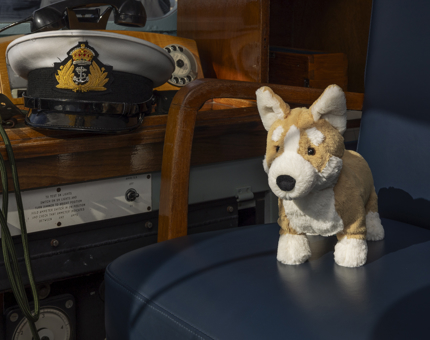 A corgi soft toy is on the Captain's chair in the Bridge. There is a Captain's hat next to it.