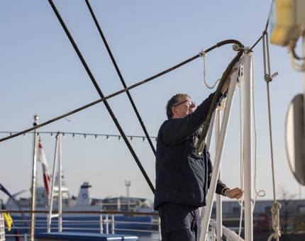 A Maintenance team member attaching a rope to the awning on the Verandah Deck.
