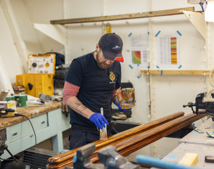 A maintenance team member varnishing handrails.
