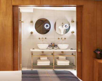 A view of a bathroom from a bed in a Duplex Cabin aboard Fingal. The bathroom had two circular mirrors and a double sink. 
