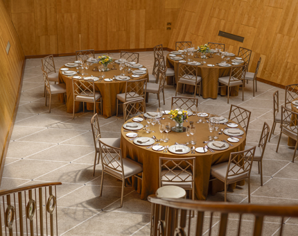 From the staircase, a view of Fingal Hotel's Ballroom. There are four tables set for dinner. The tables have gold tablecloths.