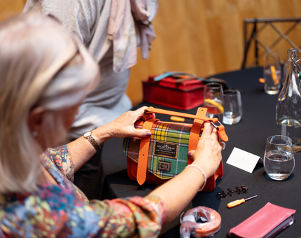 A lady adding orange straps to a handbag she is making at the Islander bags and Harris Gin event on Fingal.