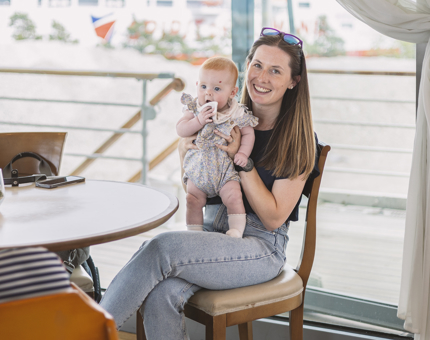 A woman sitting in the Tearoom holding a baby.