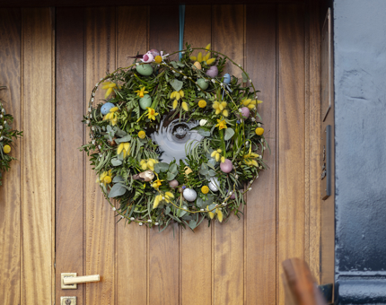 A wooden door, the entrance to Fingal Hotel, with an Easter themes wreath on it.