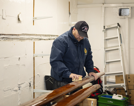 A Maintenance team member sanding wooden handrails.