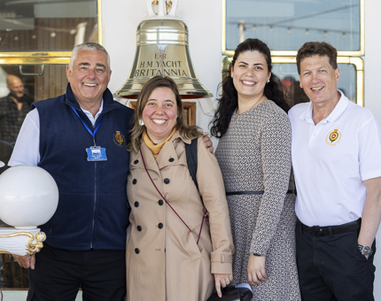 Two visitors posing for a photo with two ex-Royal Yachtsmen at Britannia's Bell.