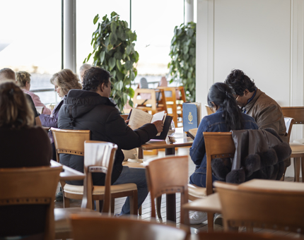 A view over the Royal Deck Tearoom of visitors sitting at tables and looking at menus. 