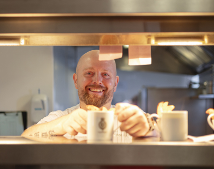 A Chef is placing a mug of soup on the pass, ready to be served in the Tearoom.