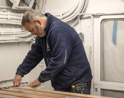 A Maintenance team member sanding handrails.