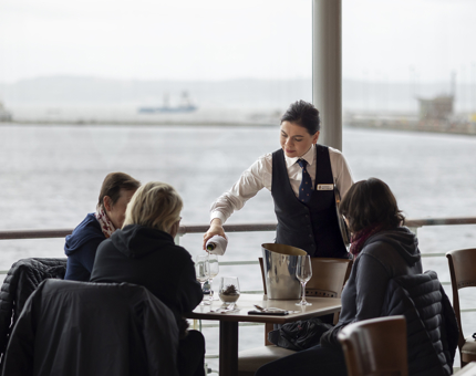A server in the Tearoom pouring Champagne into glasses for guests. 