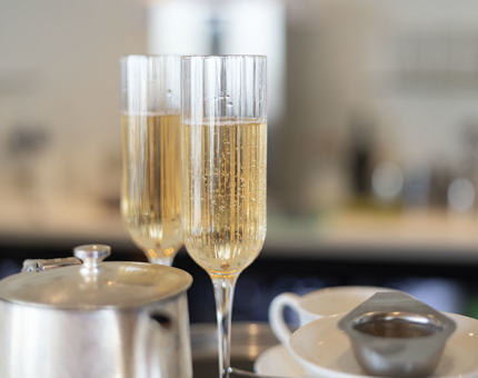 Two glasses of rose sparkling wine and a silver teapot in the Royal Deck Tearoom. 