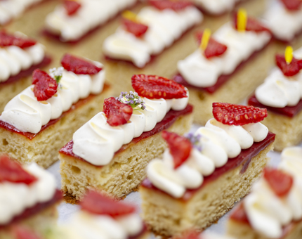 A close up of a tray of vanilla and raspberry cakes. 