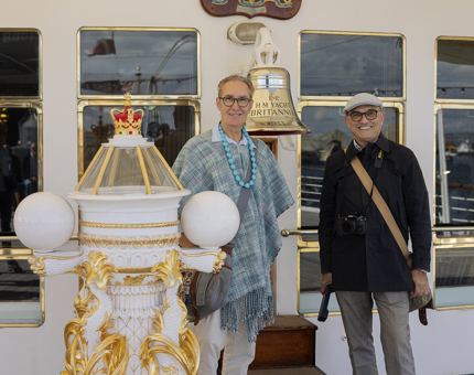 Two visitors pose for a photo next to Britannia's Bell and binnacle in the Port of Leith. 