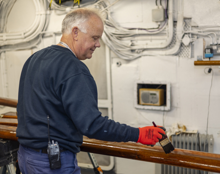 Handrails being varnished by a Maintenance team member.