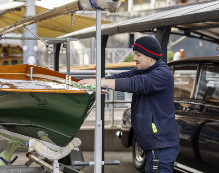 A man cleaning down a keelboat on the quayside.